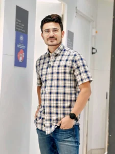 Image of Rohit Upadhya wearing a chcekered shirt and a blue jeans standing in a mall changing room