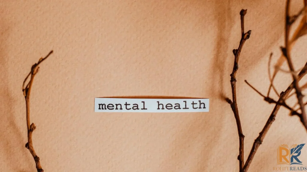 A piece of paper with the words "mental health" written on it, placed between two bare branches on a beige background.